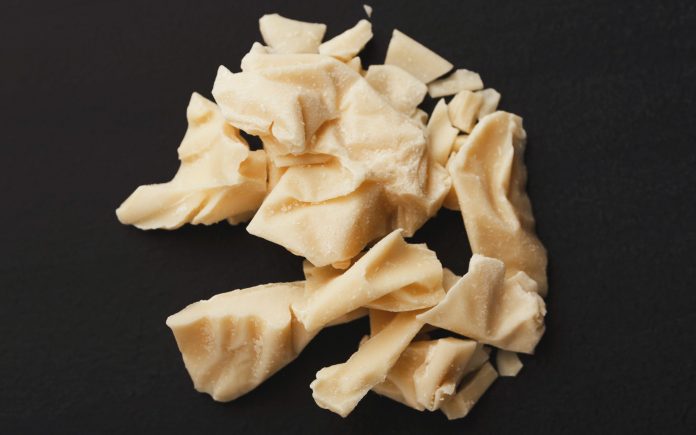 Top view on pieces of cocoa butter isolated on black background. Heap of white chocolate, cutout